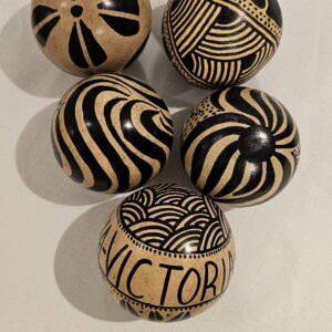 Hand-carved calabash gourd balls with black and beige intricate patterns.