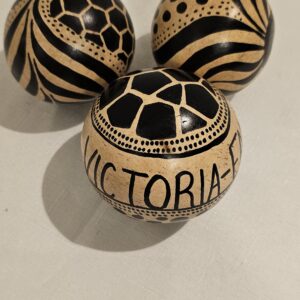 Hand-carved African decorative calabash gourd balls with black and beige patterns.