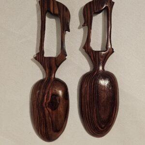 Hand-carved wooden serving spoons with giraffe-shaped handles made from dark wood, ideal for kitchen and dining decor.